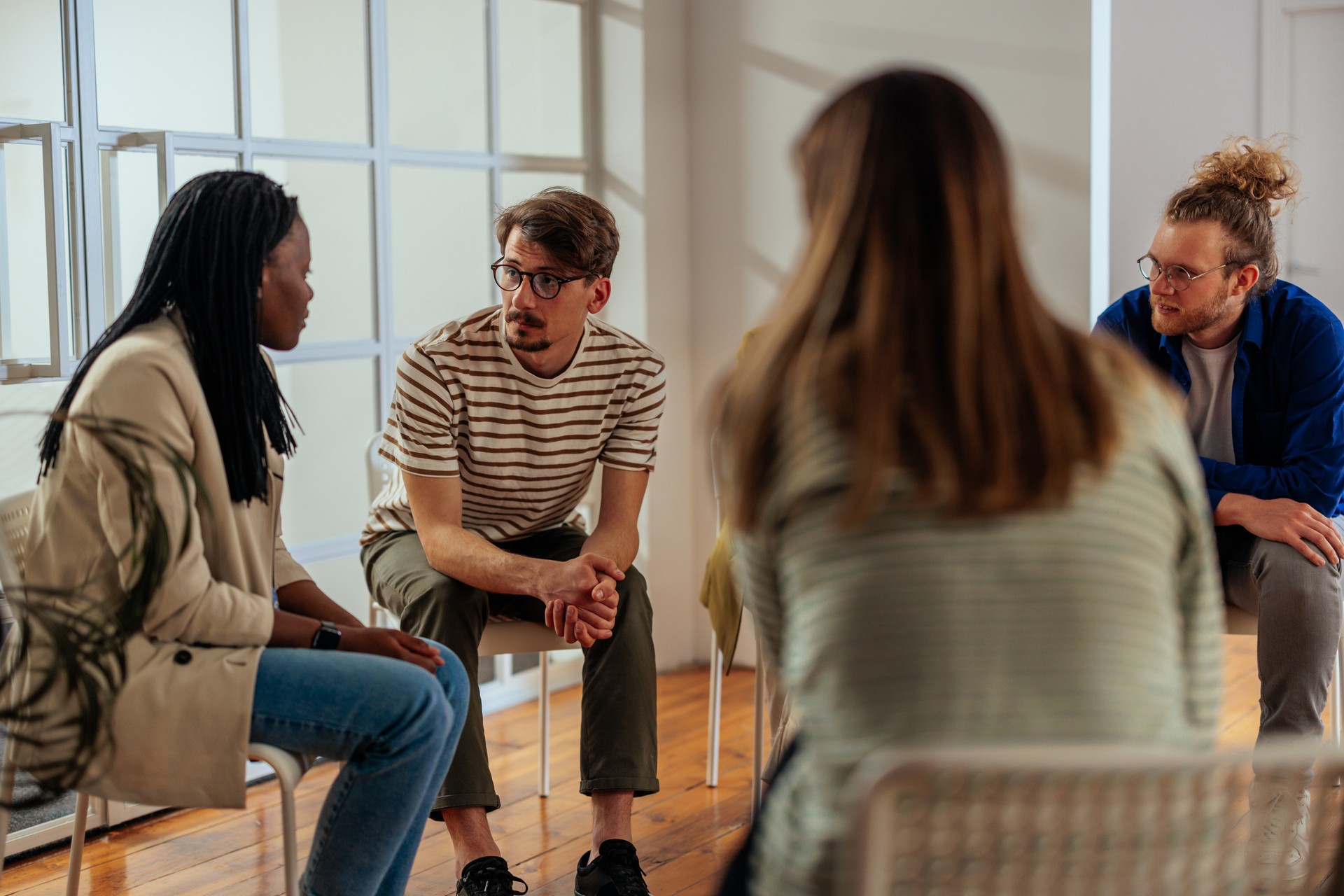 Multiracial group of people talks during therapy session